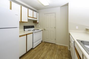 A kitchen with white appliances and wooden floors.at Sunset Ridge, West Jordan, 84081